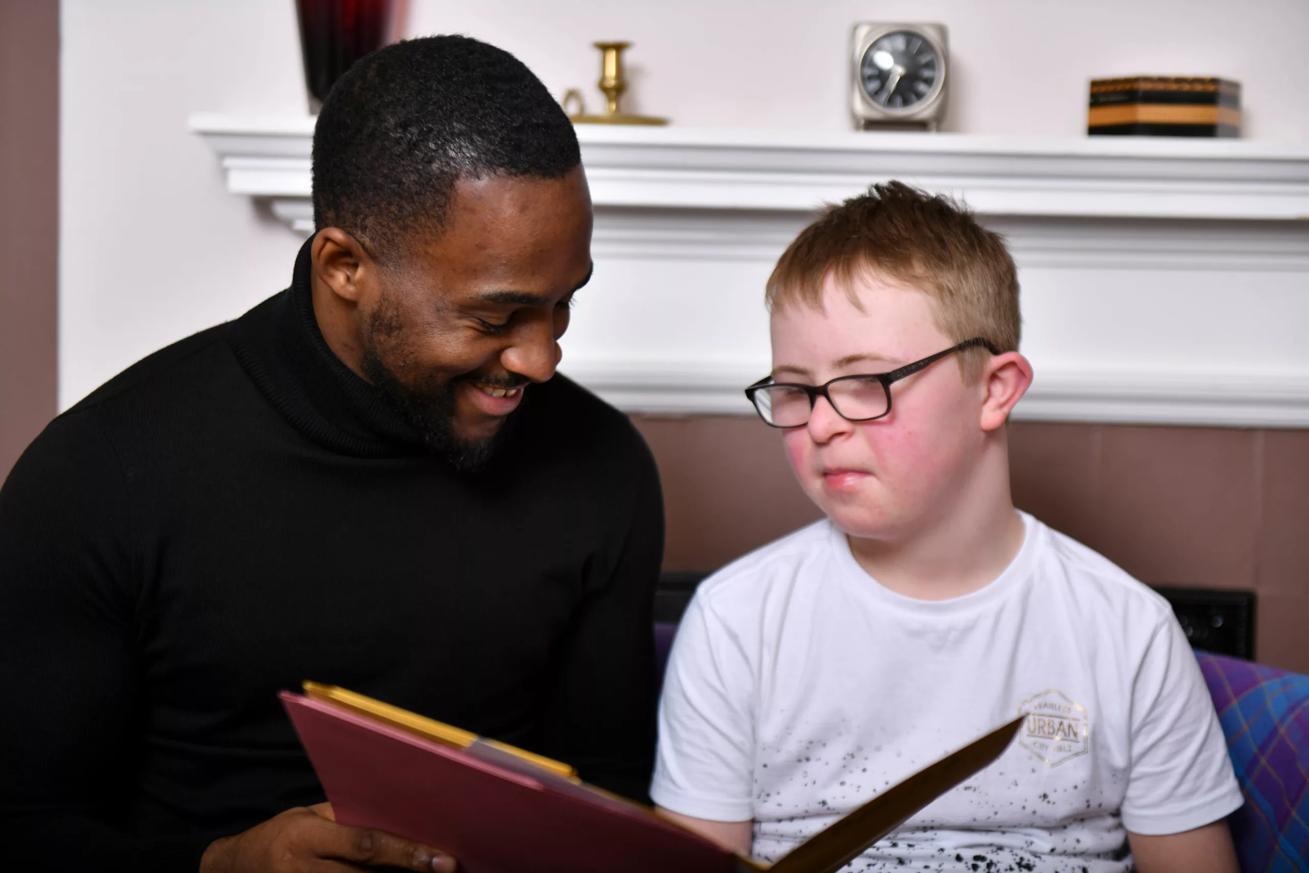 Male professional holding files chats to a boy with disabilities in a home