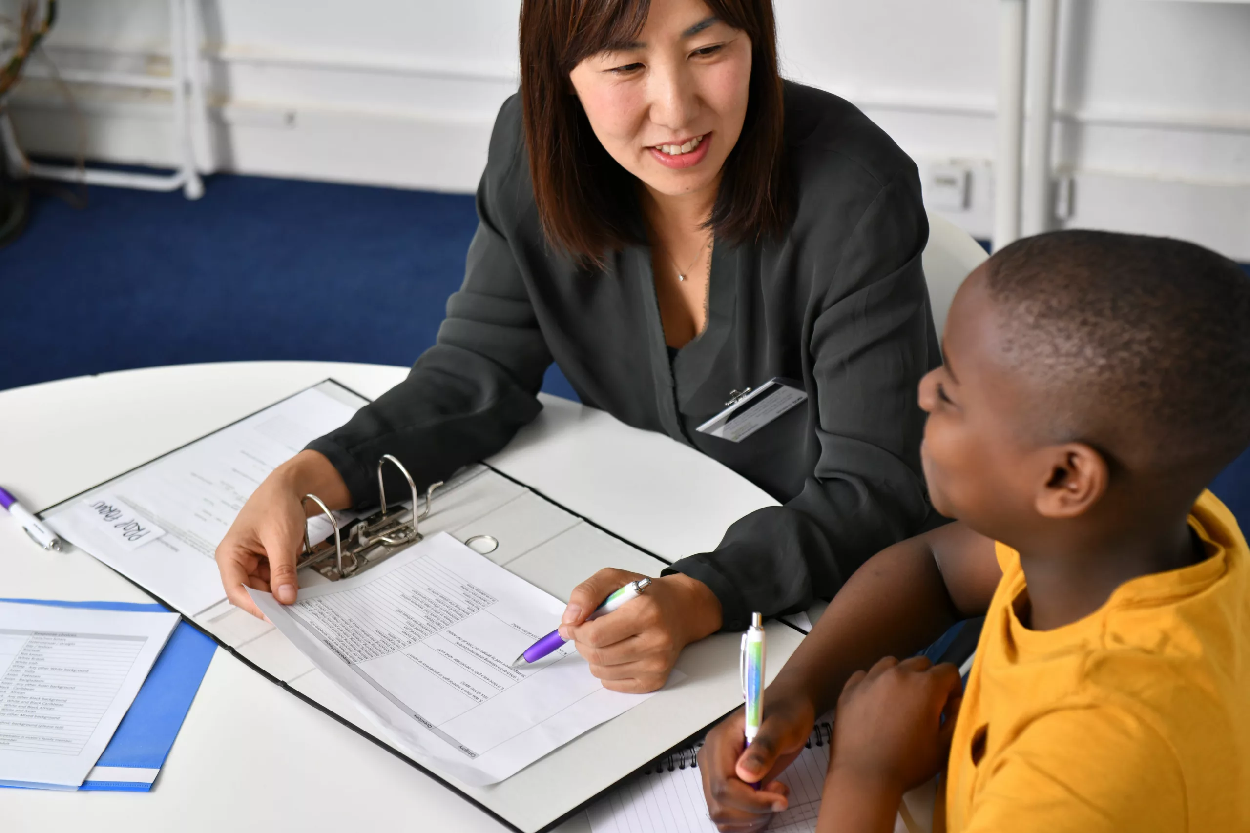 Female professional discusses a paper document at a table with a young boy