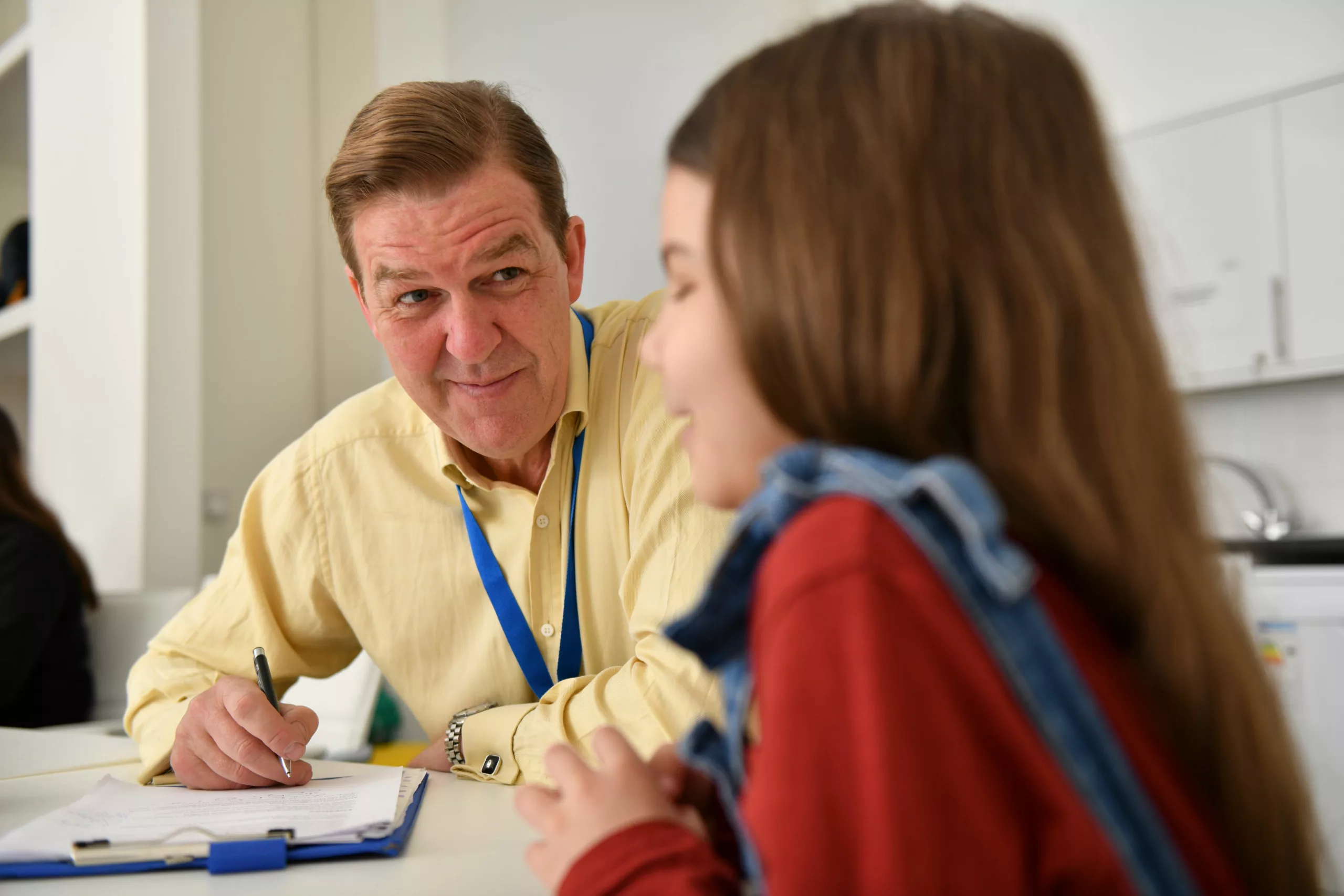 Professional speaking to a child sat at a table in an office