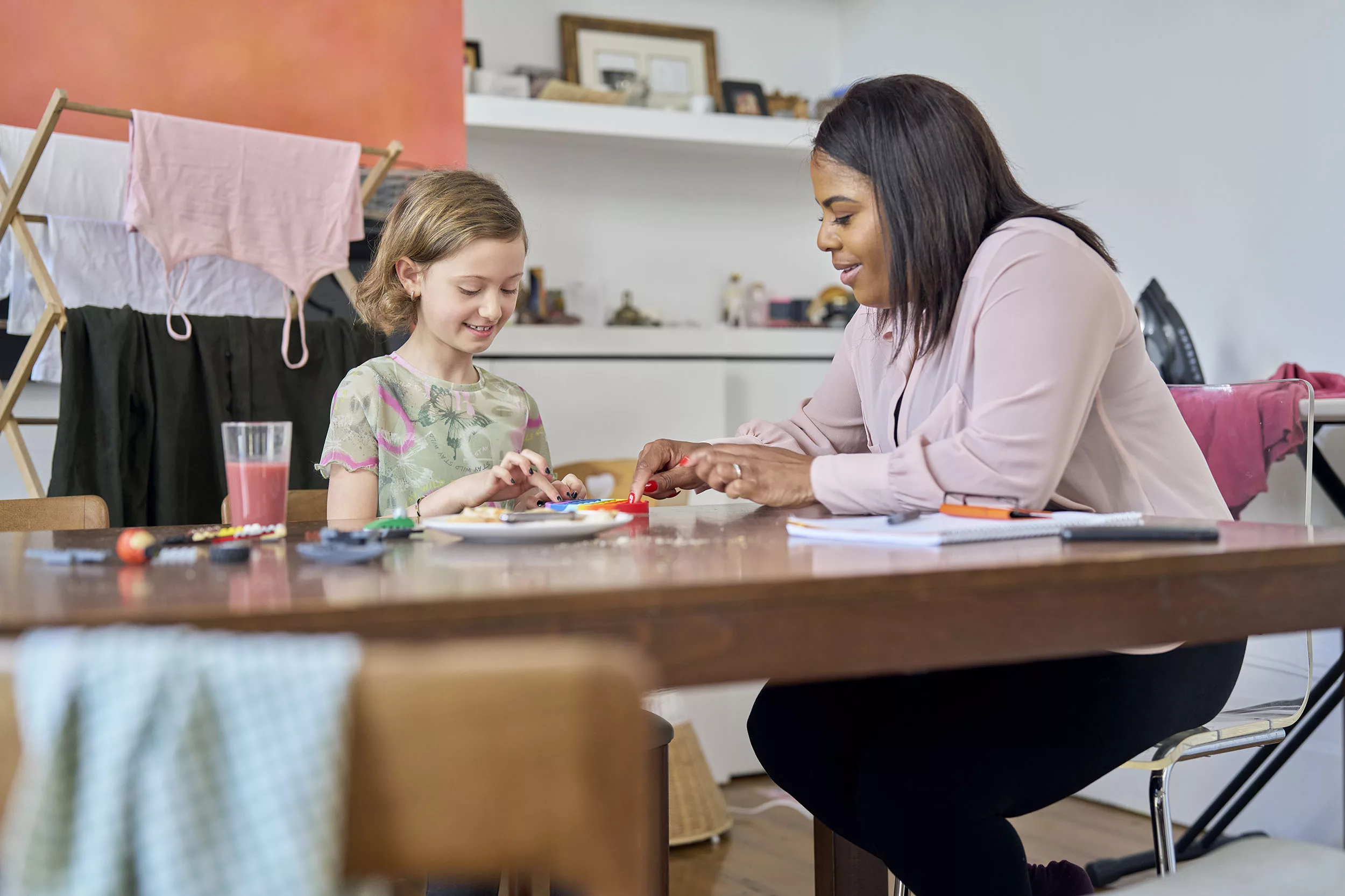 Social worker and child looking at a toy on a kitchen table