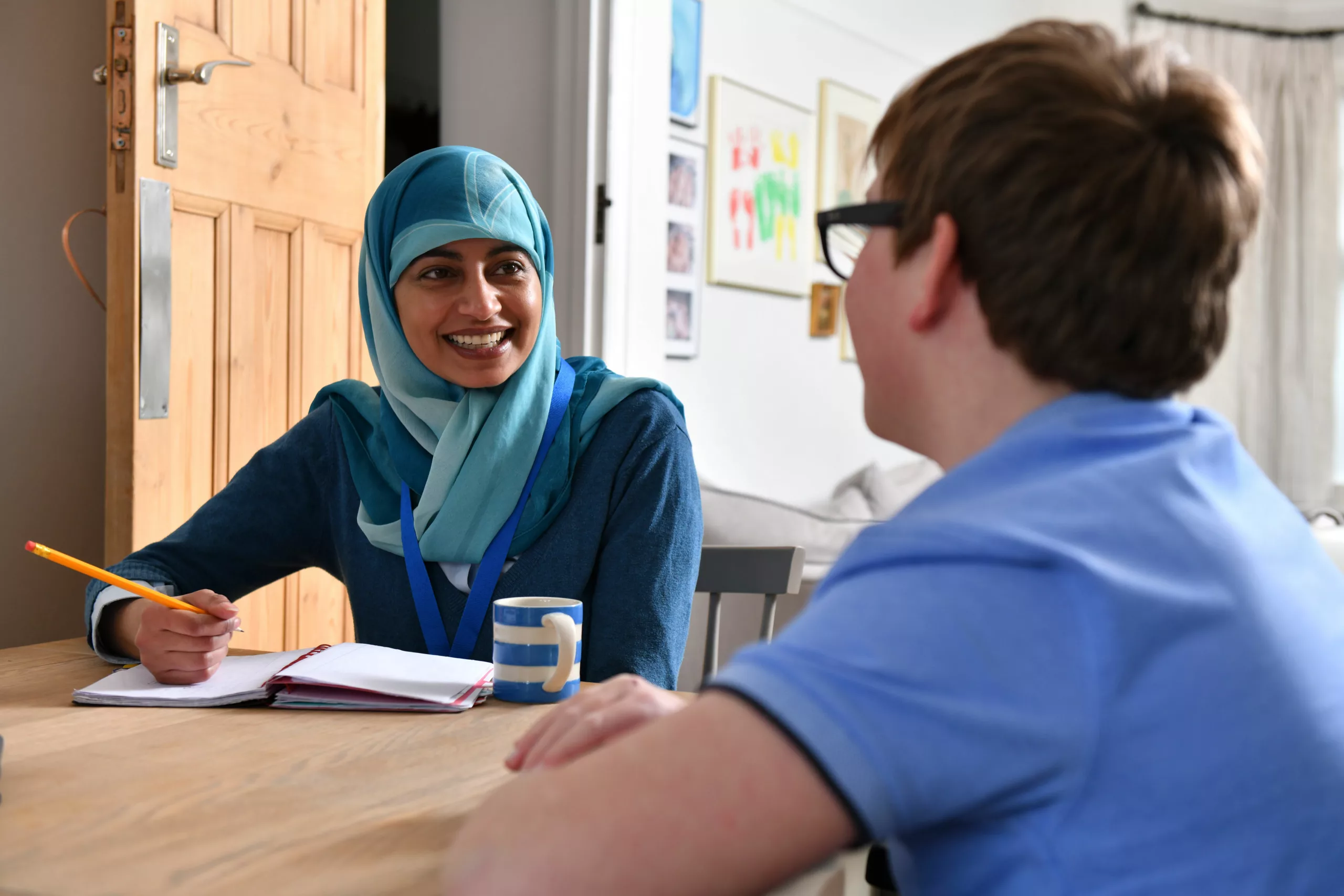 Social worker speaking to child sat at kitchen table