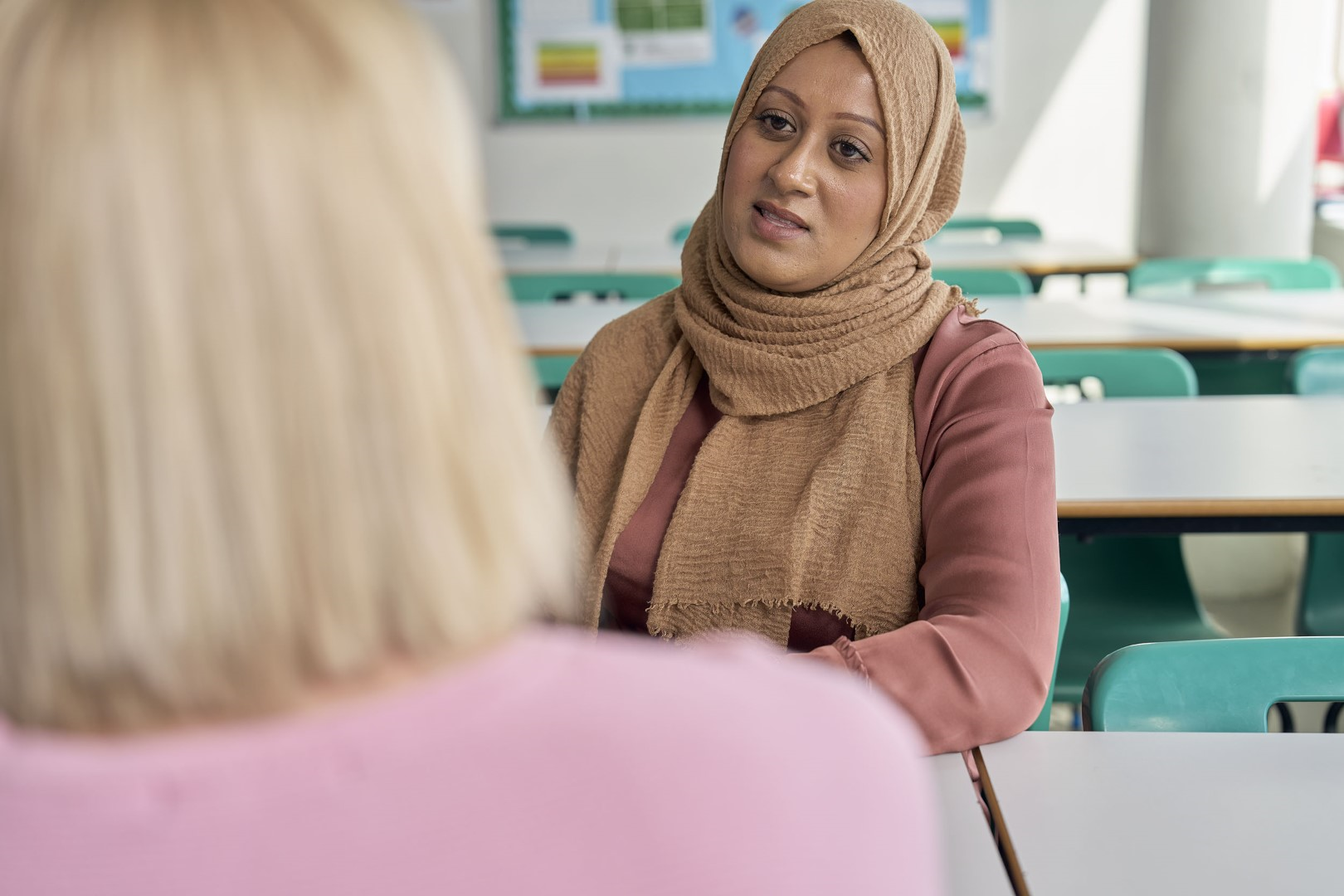 Mum and female teacher speak in a classroom