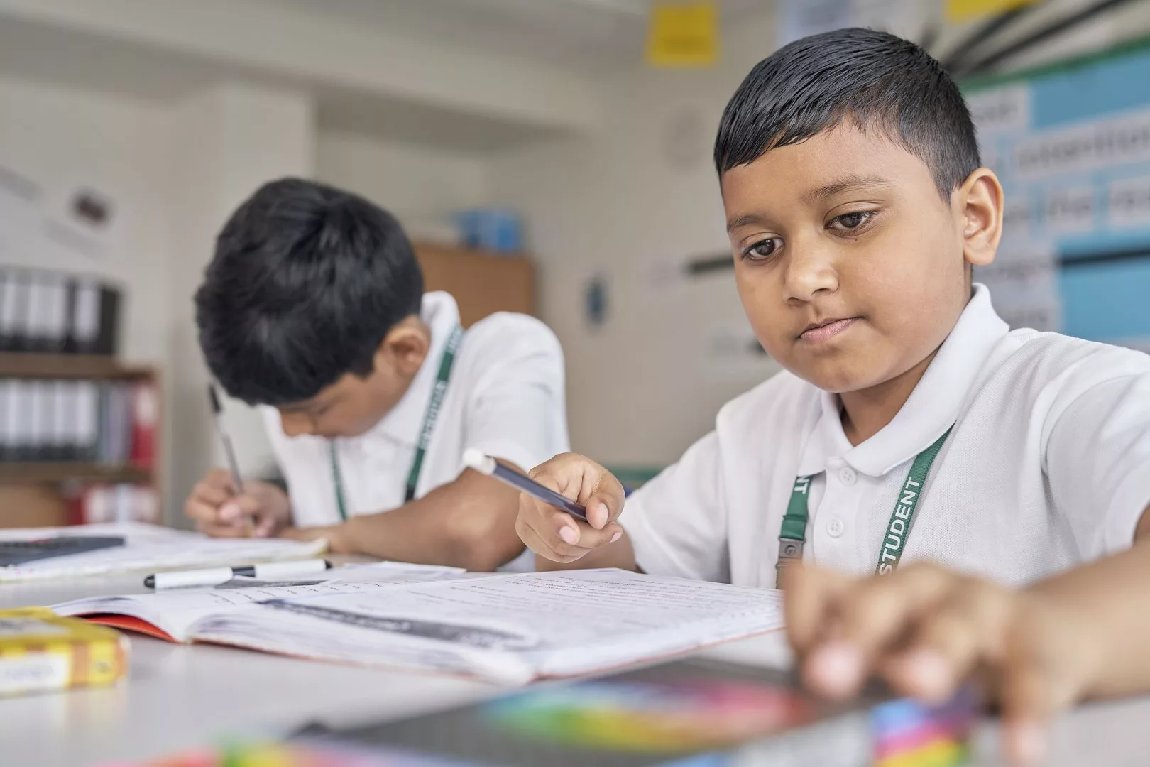 Two young boys at school sat behind a desk working