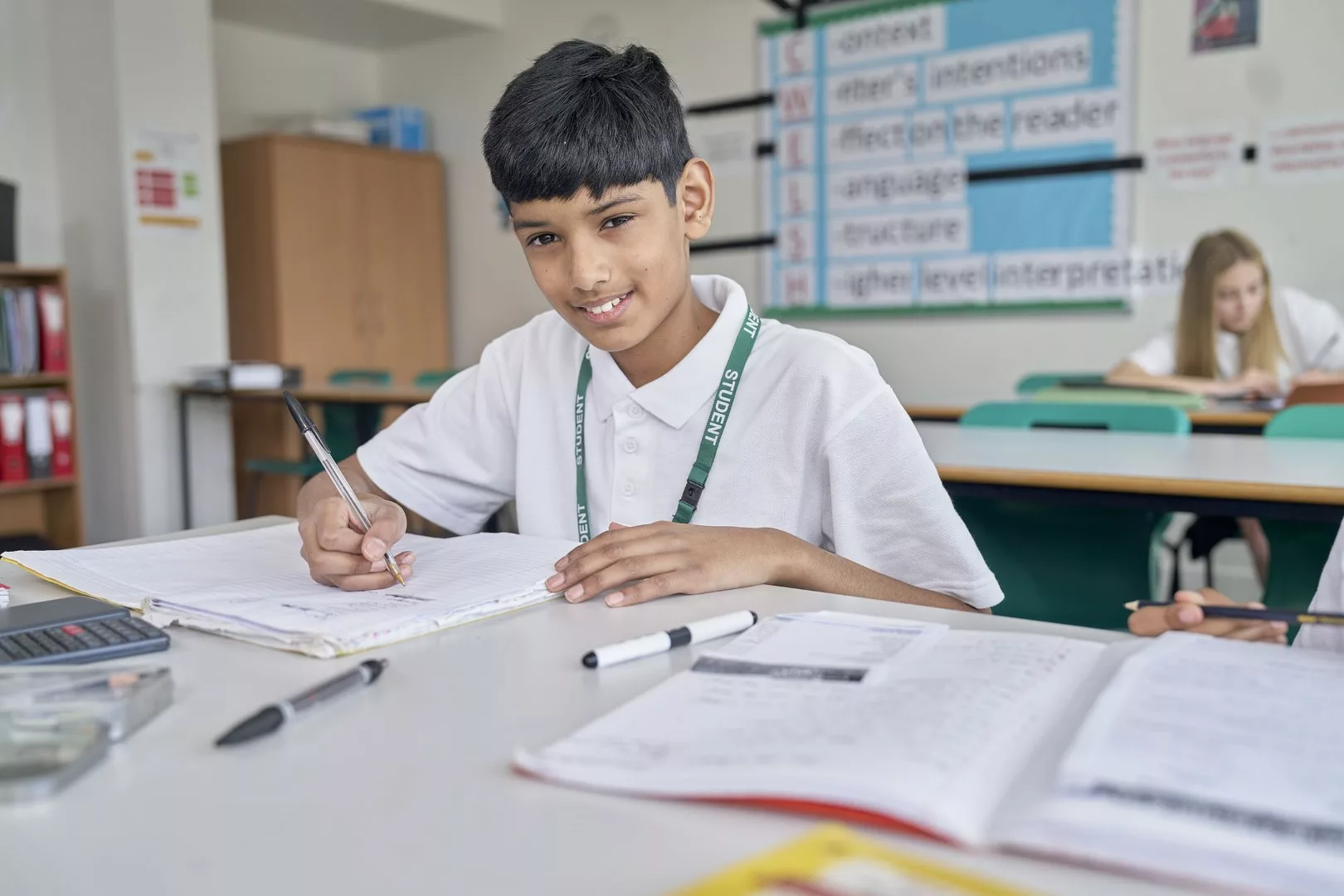 Young boy smiles whilst working in a classroom