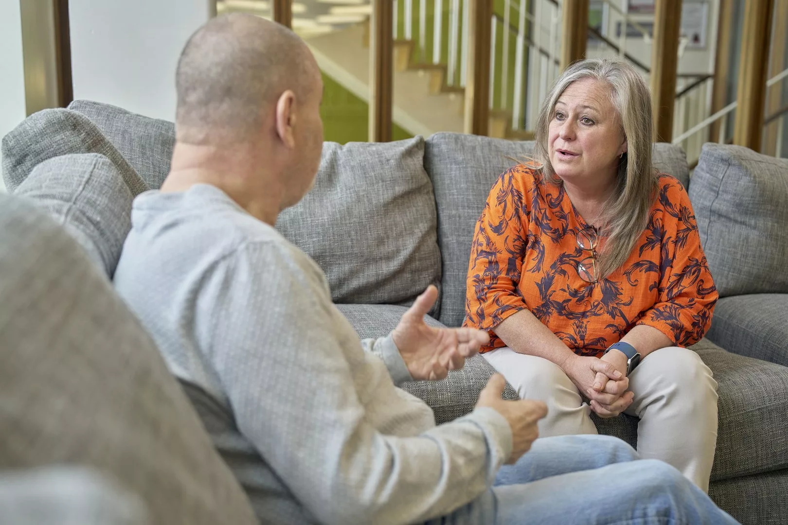 Adult male speaks to a female professional on a sofa