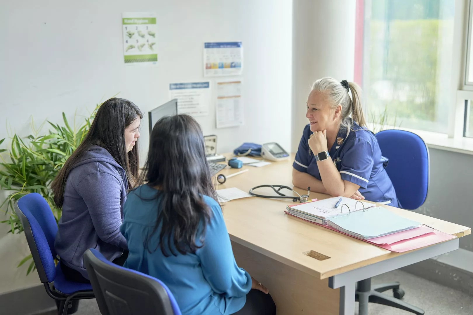 Nurse talks to mother and daughter at desk