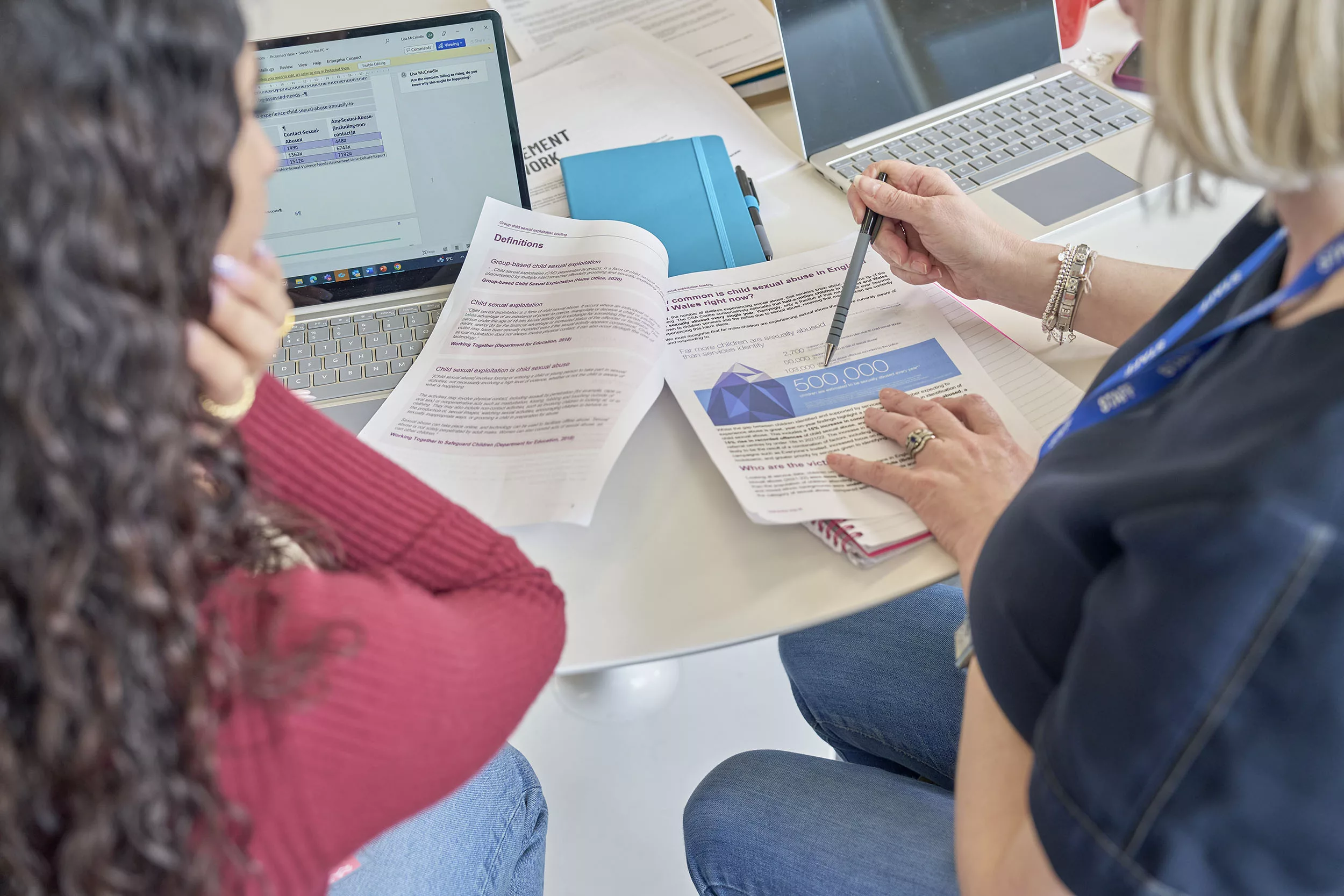 Two social workers looking at an infographic in a printed briefing document