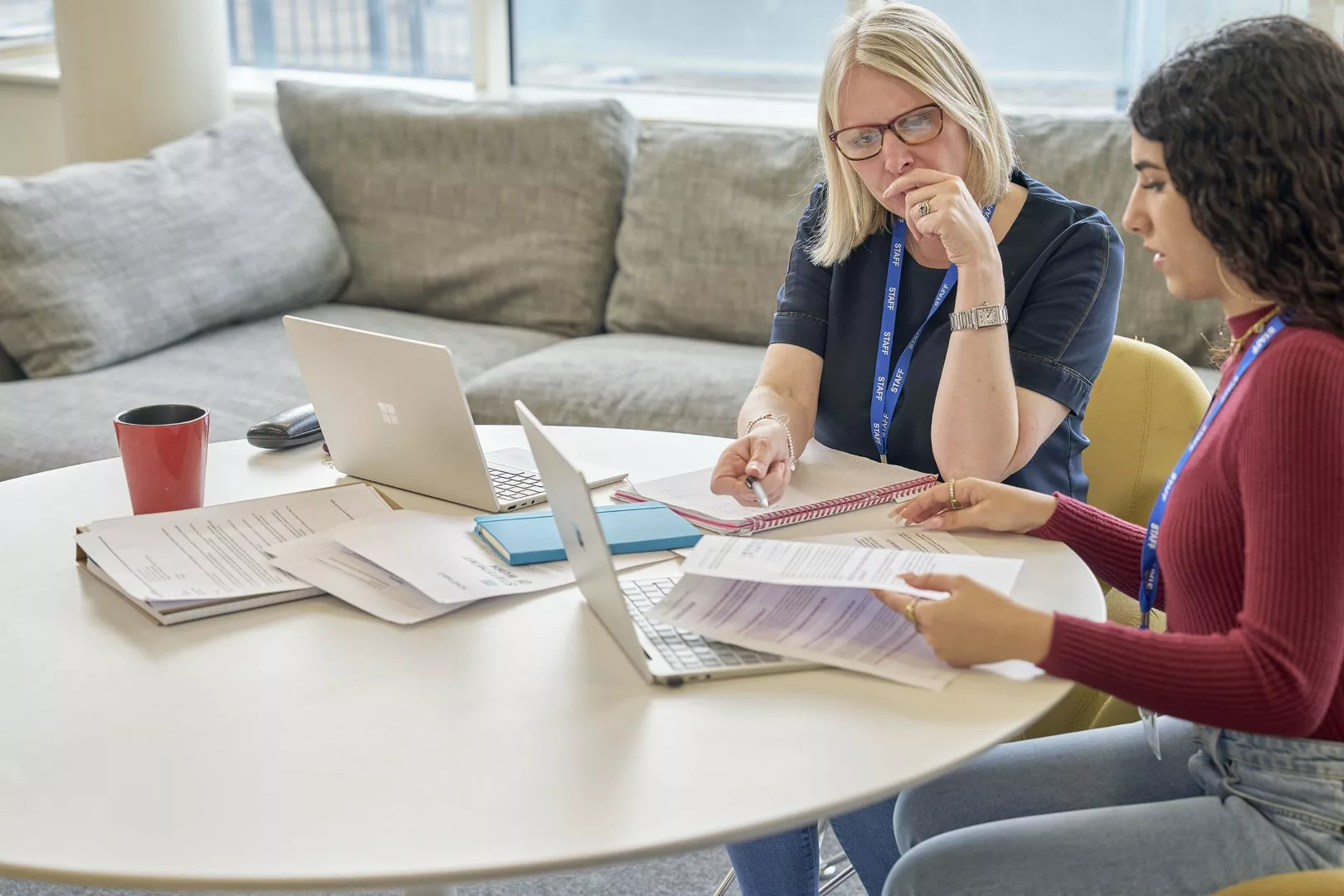 Two professionals having a conversation around a desk