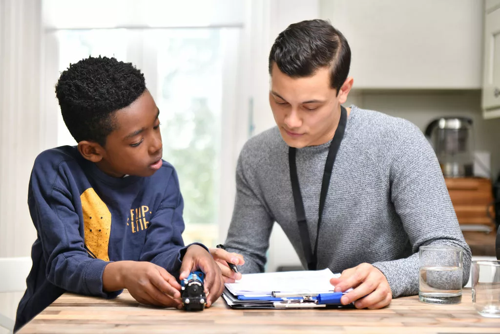 Young boy with male professional looking at a document on a table