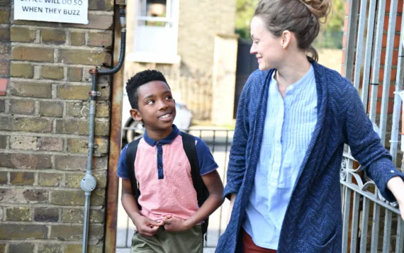 Teacher leading student through a school gate