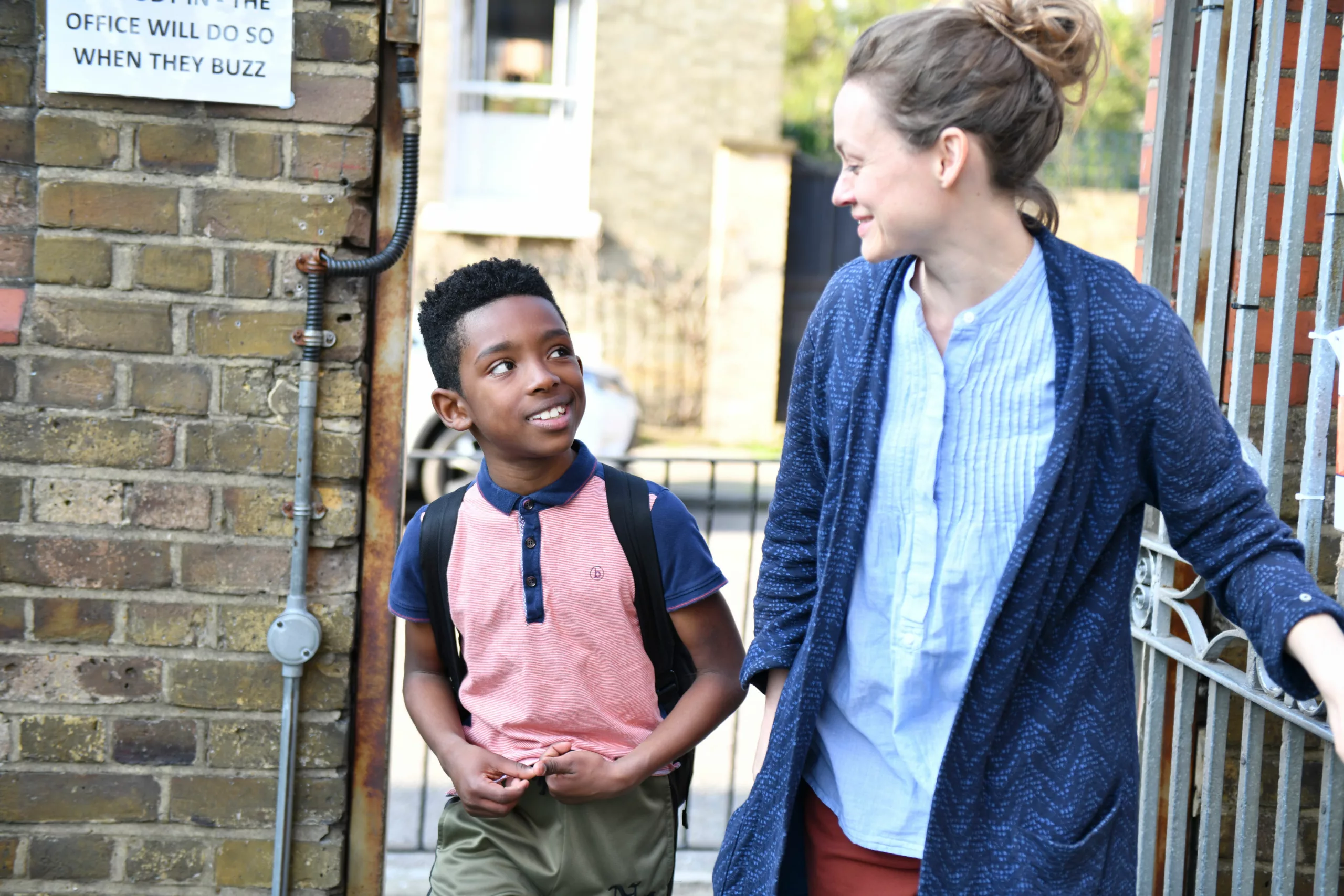 Teacher leading student through a school gate