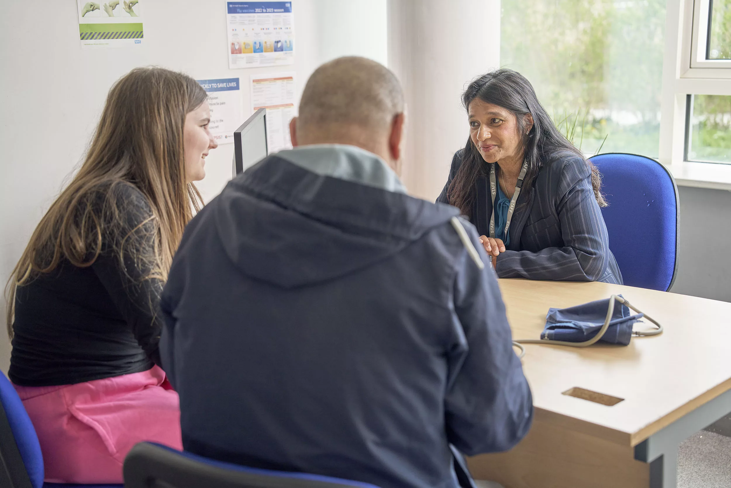 GP speaking to parent and young person in doctor's office