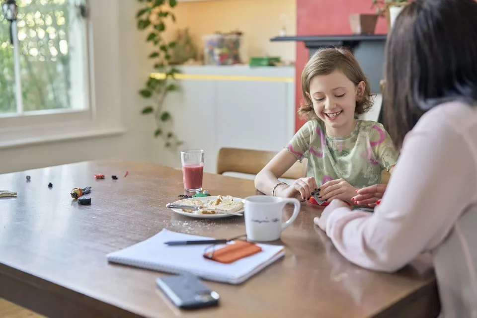 Young girl sits at kitchen table with female professional