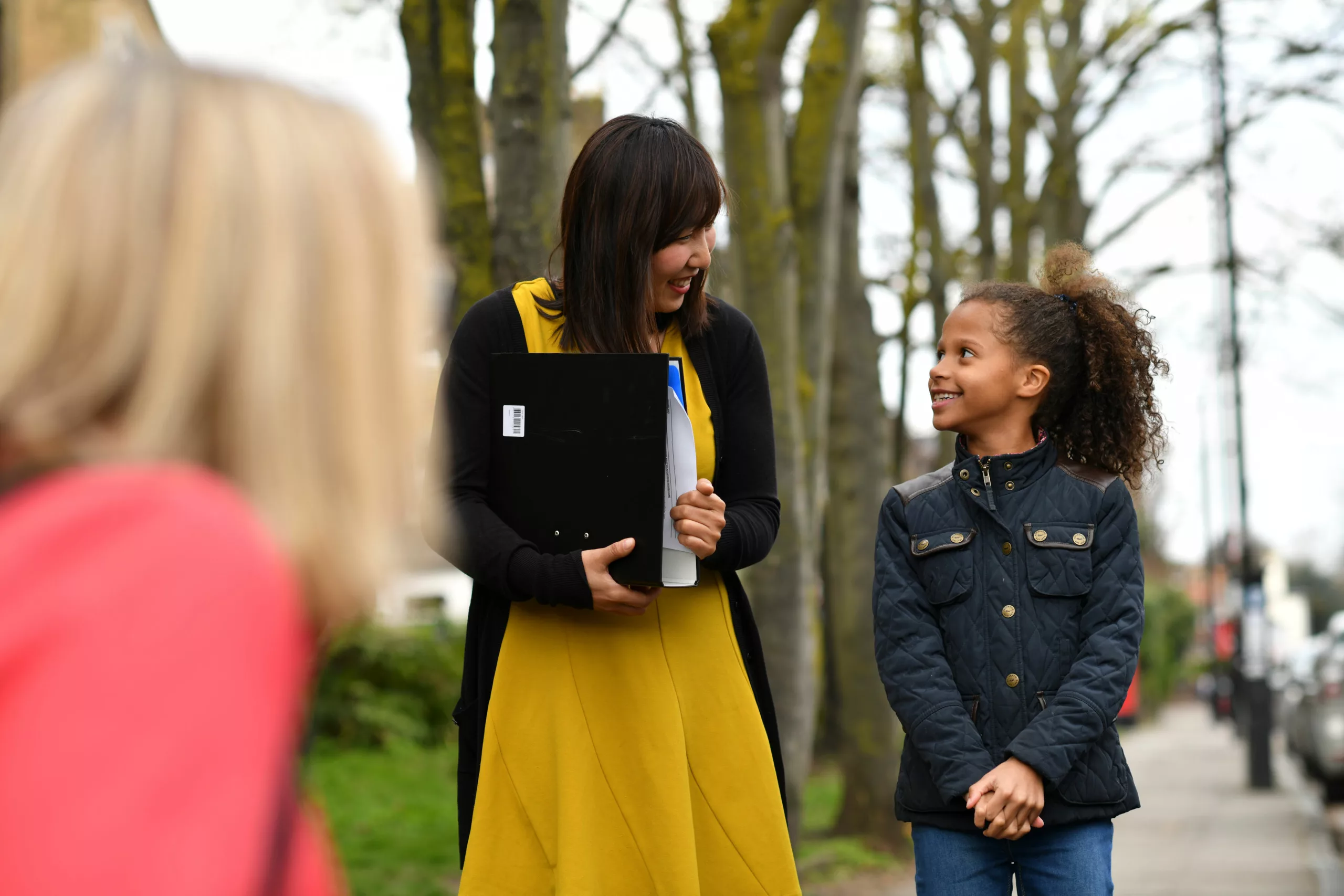 A female professional and young girl look at each other and chat walking down the street