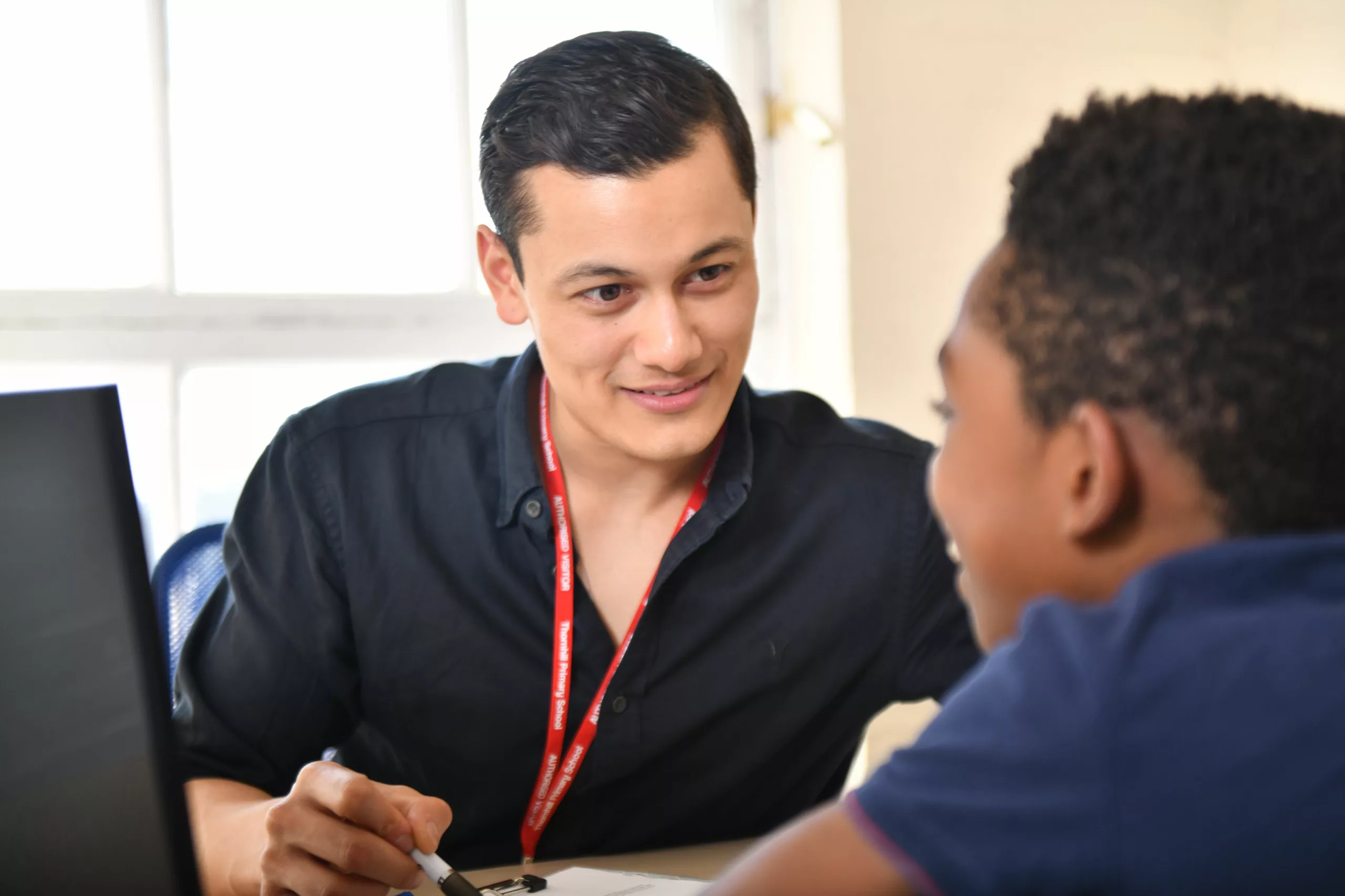 Male professional speaks to a young boy in an office