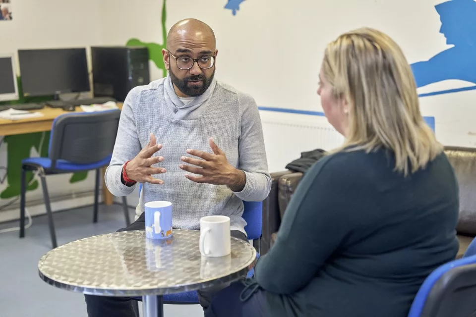 Two professionals speak around a table in a youth centre