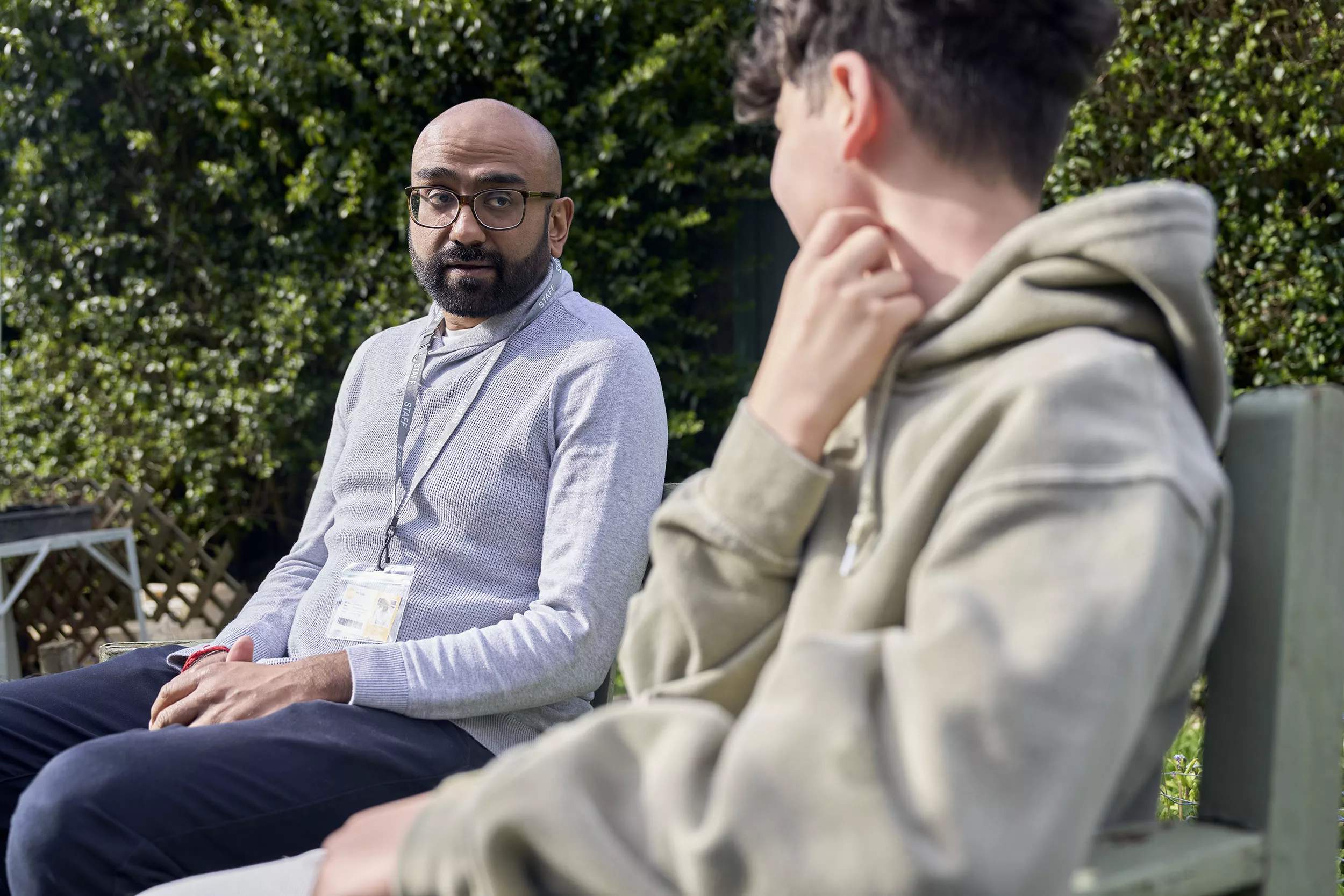 Professional speaking to a child sat on a garden bench