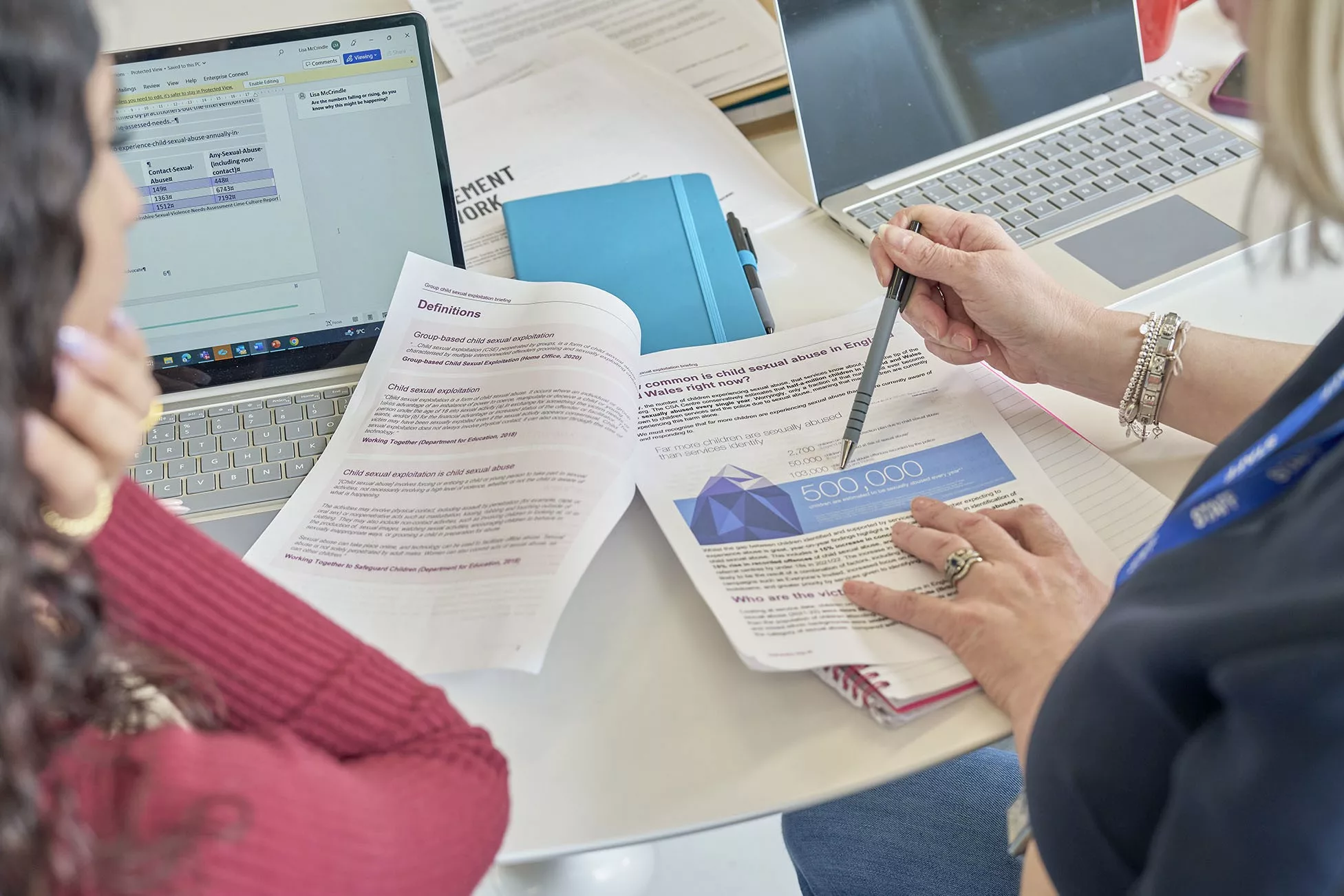 Two social workers looking at an infographic in a printed briefing document