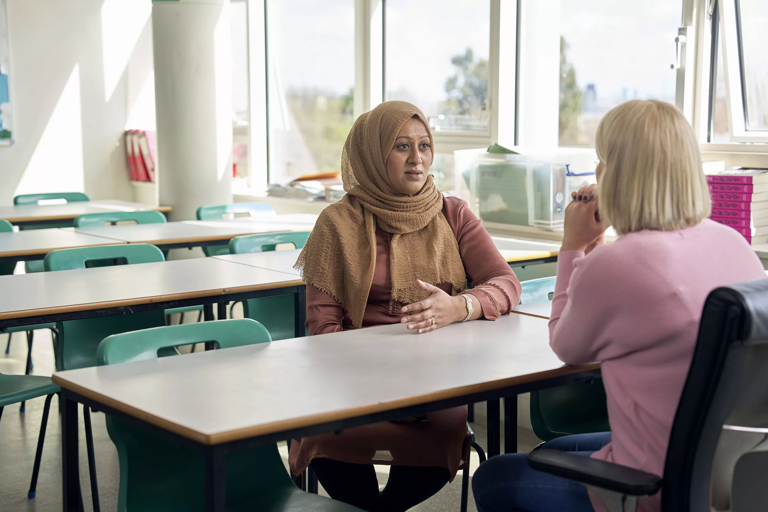 Parent speaking to a teacher in a classroom