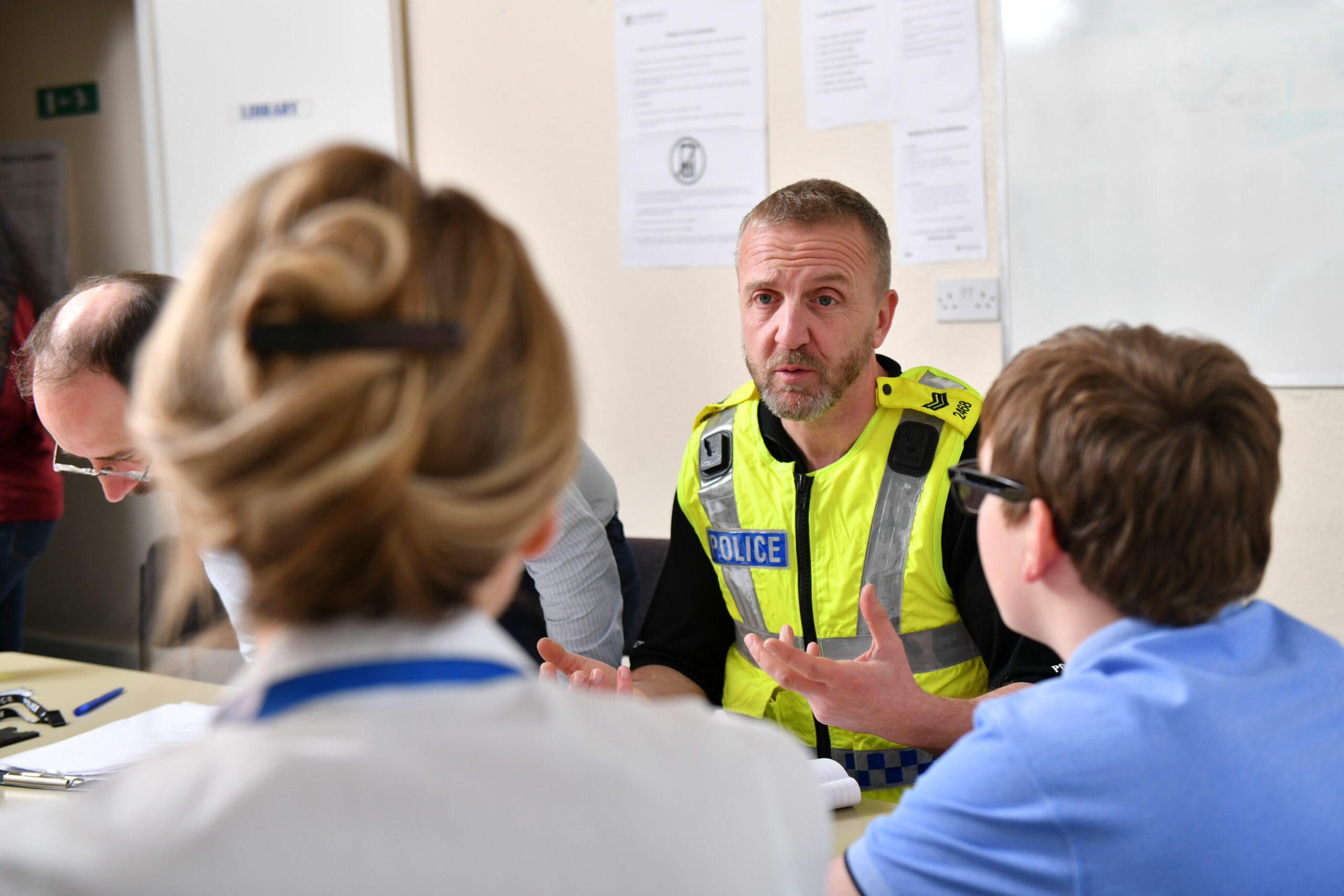 Police officer talking to a child and a professional at a table