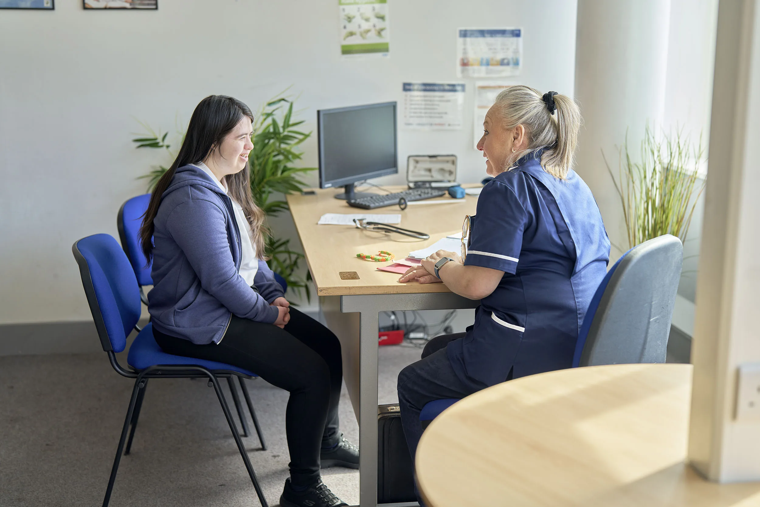 Nurse speaking to a girl in a GP's office