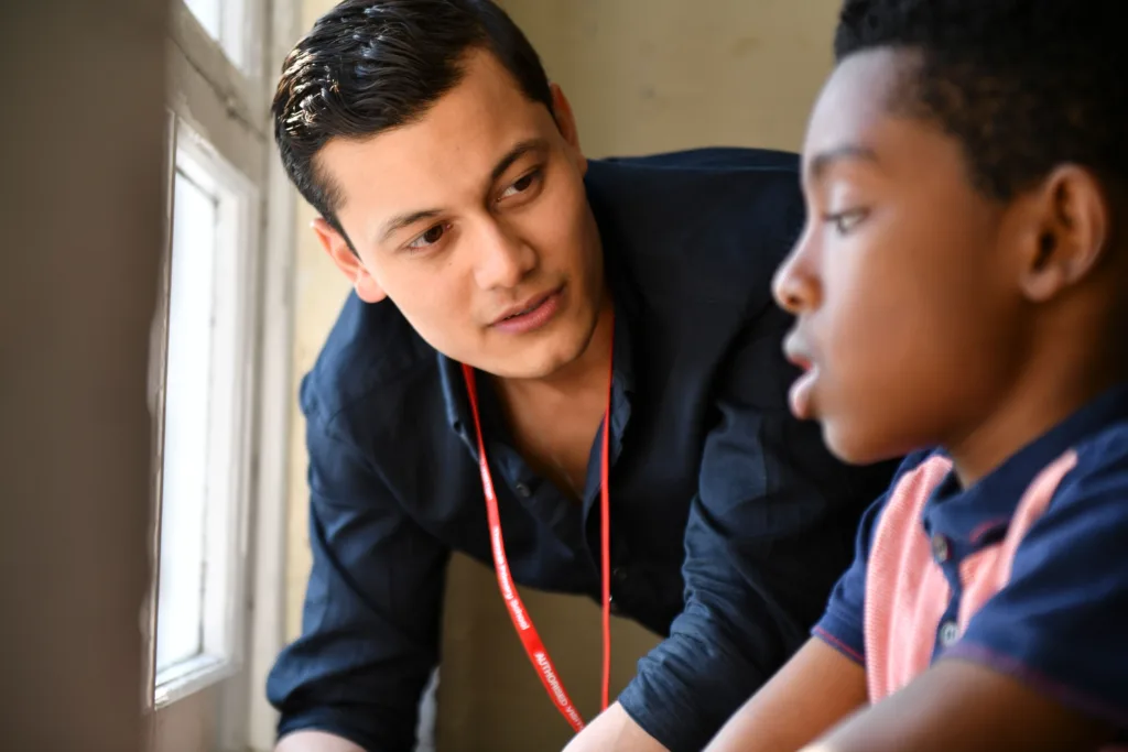 Boy looking out of the window with male professional leaning down to speak to him